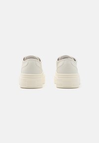 Baskets en cuir blanc au toucher lisse, à bout rond et semelle en caoutchouc épaisse. Présente un logo discret sur le talon avec un design épuré.