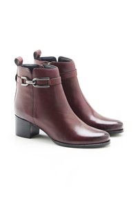 Botas de tobillo de cuero burdeos con una textura suave, punta redonda, tacón de bloque de altura media y detalle de hebilla plateada en la correa.