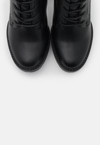 Bottes noires à lacets en cuir texturé. Pointes arrondies avec couture renforcée et finitions lisses à l'avant et sur les côtés.