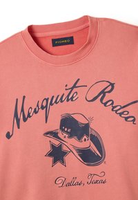 Sudadera de color coral con cuello redondo y acabado de canalé, que presenta un texto gráfico en azul marino "Mesquite Rodeo" y un diseño de sombrero de vaquero.