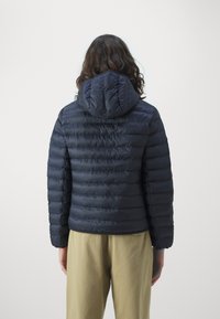 Marinblå puffjacka med huva, kviltad design, elastiska ärmslut och en figurnära nederkant. Tyget verkar mjukt med en subtil glans.