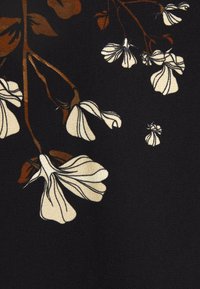 Svart tyg med ett blommönster i vitt och bruna löv, som visar en slät textur och intrikat detaljering.