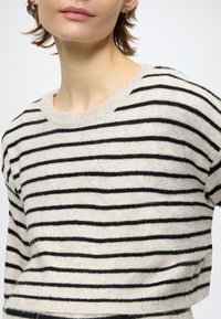 Csíkos pulóver krémszínű és fekete színvilággal, kerek nyakkivágással és rövid ujjal. Puha, texturált anyag.
