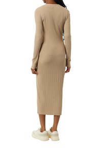 Beiges, geripptes Langarmkleid mit taillierter Silhouette, Rundhals-Ausschnitt und Rückenverschluss, kombiniert mit weißen Plateausneakern.