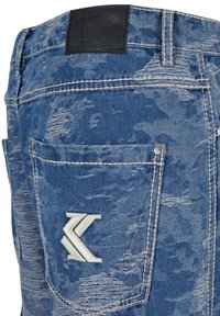Blue denim jeans featuring a distressed texture, a black leather waistband patch, and an embroidered logo on the back pocket.