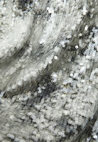 Tissu en sequins argentés présentant une surface brillante et texturée avec des sequins circulaires superposés disposés très proches les uns des autres.