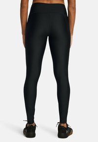 Svarta leggings med hög midja, tillverkade av ett mjukt, stretchigt material. Har en figursydd design och stängs vid anklarna.
