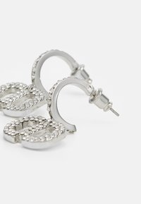 Pendientes de aro de plata con un diseño de doble "C", adornados con rhinestones transparentes para un brillo adicional. Textura de metal suave y acabado pulido.