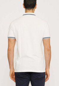 Polo bianco con un design classico, rifinito con accenti a strisce blu navy sul colletto e sulle maniche. Maniche corte, vestibilità media, materiale in cotone.