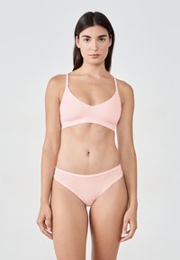Ensemble de bralette et bikini rose clair en tissu lisse. Présente de fines bretelles réglables et une ceinture élastique avec un design minimaliste.