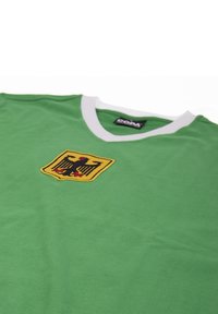 Groene trui met een witte V-halskraag, voorzien van een gele en zwarte geborduurde embleem met een adelaar. Gemaakt van een lichtgewicht stof.