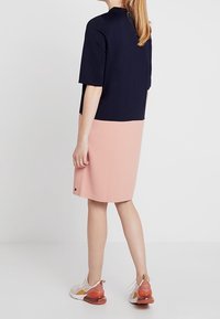 Šaty s barevným blokováním, které mají námořnický vršek a sukně v tělové růžové barvě, vyrobené z měkké látky, se krátkými rukávy a uvolněným střihem.