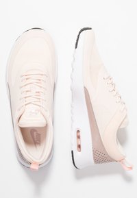 Light pink athletic shoes with mesh and synthetic materials, rounded shape, white sole, and transparent air cushioning detail.
