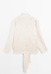 Blouse longue manches en satin crème avec col et détail de tissu prolongé suspendu à l'ourlet arrière, vue de dos.