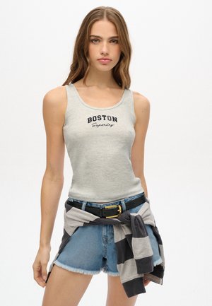 Lys grå ribbet tanktop med "BOSTON" trykt i sort, parret med blå denimshorts og en grå stribet sweatshirt bundet om taljen.
