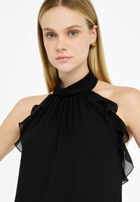 Top a fascia nera realizzato in un tessuto leggero, con dettagli arricciati lungo il girocollo e le spalle, caratterizzato da una texture morbida.