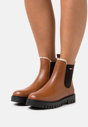 Bruine leren enkellaarsjes met elastische zijpanelen, witte imitatiebontafwerking en een getextureerde zwarte rubberen zool. Geen zichtbare branding.