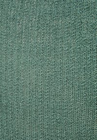 Tecido texturizado numa cor verde-azulado suave, apresentando um padrão de malha com finas ranhuras e um acabamento ligeiramente brilhante.