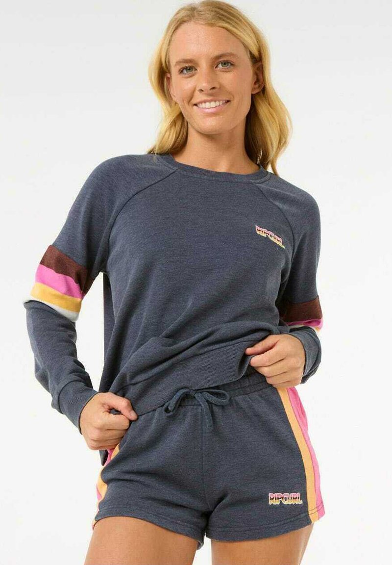 Sweatshirt en short set in marineblauwe stof. Bevat meerkleurige strepen op de mouwen en zijkanten, en een logo op de voorkant van het shirt.