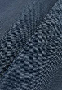 Gros plan sur un tissu tissé bleu foncé montrant une texture fine et des plis diagonaux.