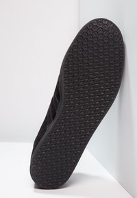 Baskets noires avec une semelle en caoutchouc texturée à motif nid d'abeille, et une tige élégante en matériau doux.