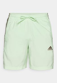 Ljust gröna sportshorts med elastiskt midjeband, snörning, sidofickor och brunt Adidas-logo i nedre högra hörnet.