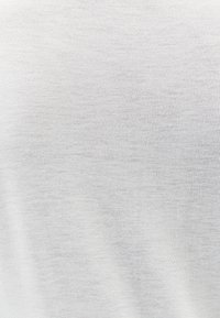 Biała dzianina z delikatną, równą teksturą i subtelnym przeszyciem. Lekka i gładka, odpowiednia na codzienne ubrania.