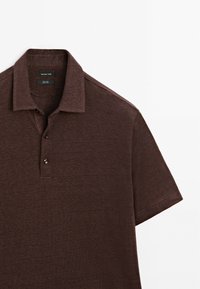 Polo shirt marrone a maniche corte realizzato in tessuto testurizzato, caratterizzato da un colletto classico e una chiusura a tre bottoni con bottoni scuri.
