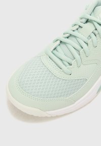 Light green athletic shoe featuring a mesh upper, textured accents, padded collar, and a white rubber sole. Intricate pattern on material.