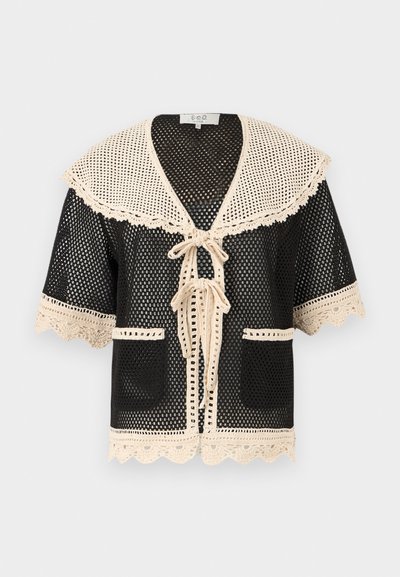 Μαύρη ανοιχτή πλεκτή ζακέτα με κοντά μανίκια, μεγάλο κρεμ γιακά από κροσέ, διακοσμητική τρέσα, μπροστινούς δεσμούς, δύο τσέπες και κυματιστά τελειώματα.