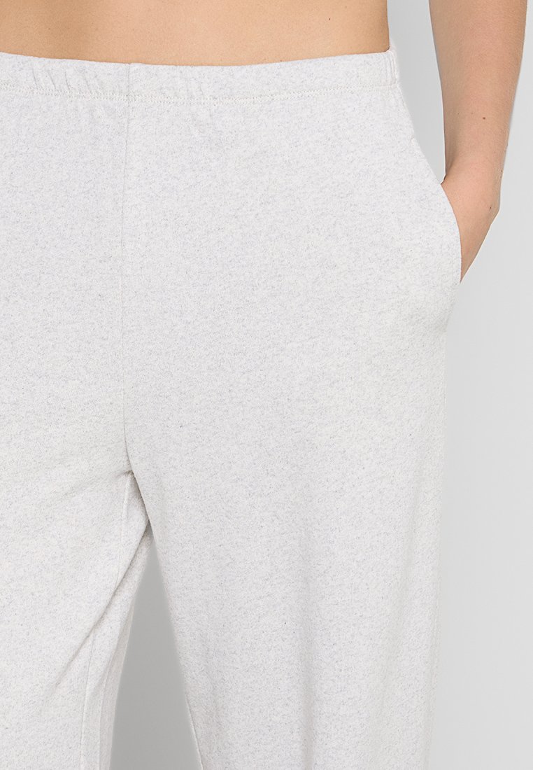 Pantaloni sportivi grigi chiari realizzati in tessuto morbido, con vita elastica e tasche laterali, caratterizzati da una superficie leggermente testurizzata.