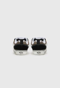 Vue arrière de baskets avec une palette de couleurs noire, marron et blanche. Comprend un col rembourré blanc, des accents en daim noir et une semelle en caoutchouc.