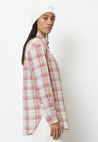 Plaid shirt in pink, white, and beige. Long sleeves, buttoned cuffs, and curved hem. Soft fabric texture with a relaxed fit.