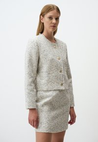 Weißes und blaues strukturiertes Tweed-Jacket mit goldenen Knöpfen und einem cropped Design, kombiniert mit einem passenden, taillierten Rock.