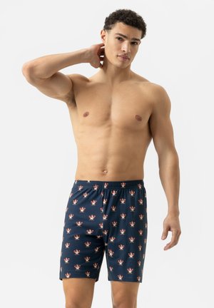 Shorts pour hommes de couleur bleu marine fabriqués en tissu doux, ornés d'un motif de fleurs rouges et blanches. Taille élastique et coupe à mi-genou.
