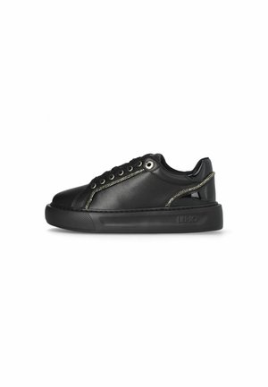 Black low-top sneaker with thick sole, lace-up front, decorative side zipper, and glossy heel accent.