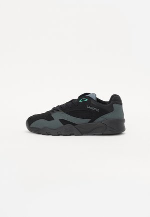 Baskets Lacoste noires et gris foncé avec lacets devant, détail œillet vert et semelle incurvée, vues de côté extérieur sur fond blanc.
