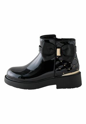 Schwarzer Lack-Ankle-Boot mit gesteppter Ferse, goldenen Nieten, einer großen Stoffschleife und dicker schwarzer Sohle.