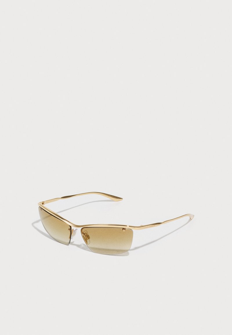 Γυαλιά ηλίου με λεπτό πλαίσιο από χρυσόχρωμο μέταλλο, καφέ φωτοχρωμικές φακοί και κομψό γεωμετρικό σχέδιο. Διαθέτουν καμπυλωτούς βραχίονες.