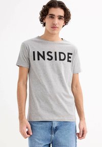 Camiseta de algodón gris con la palabra "INSIDE" en letras negritas negras, mangas cortas y un escote clásico tipo crew.