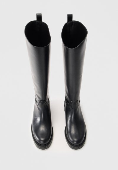 Botas de cuero negras hasta la rodilla con un acabado liso, que presentan una puntera ligeramente redondeada, una lengüeta y una suela de plataforma baja.