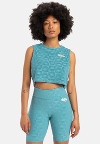 Turquoise fitness crop top with textured square pattern; paired with matching high-waisted shorts featuring similar design and logo detail.