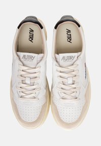 Sneaker in pelle bianca con punta perforata, dettagli in suede beige, lacci crema e targhetta nera sul tallone. Logo "AUTRY MEDALIST" sulla linguetta.