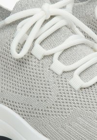 Lekkie buty sportowe z teksturowanym szarym dzianinowym wierzchem, białymi sznurówkami i gumową podeszwą. Posiadają świecące akcenty w tkaninie.