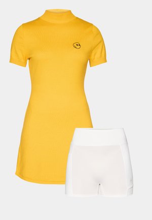 Geel kortemouwen jurk met een hoge hals en een smiley-logo, gecombineerd met witte getailleerde shorts met een gladde tailleband en subtiele accenten.