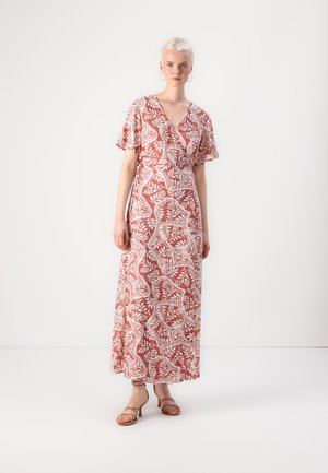 Robe maxi en corail avec un motif floral blanc, décolleté en V croisé, manches évasées et fente sur le côté, portée avec des sandales à talons à lanières.