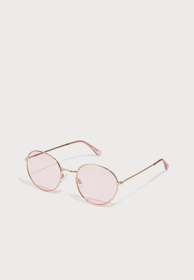 Gafas de sol redondas con montura de metal dorado, lentes rosas y puntas de las patillas en rosa claro; cuentan con almohadillas nasales ajustables para mayor comodidad.