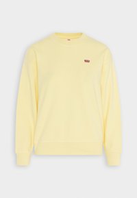Sudadera amarilla de cuello redondo hecha de algodón, con un pequeño logo rojo de Levi's en el lado izquierdo del pecho y puños y dobladillo acanalados.