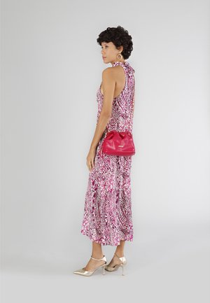 Rosa gemustertes Kleid mit Halterneck, ergänzt durch eine rote Handtasche und goldene High-Heels. Glatte Stoffstruktur sichtbar.