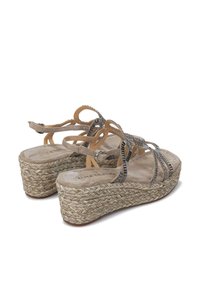 Sandalias de plataforma beige con suela de yute trenzado, que cuentan con correas entrelazadas con acentos metálicos y una plantilla suave y acolchada.